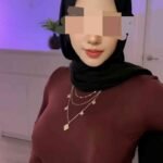 Woman in a hijab and maroon top wearing a layered necklace.