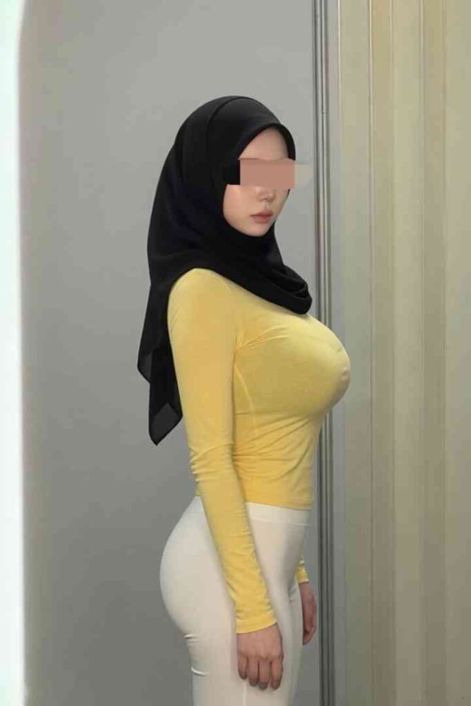 Woman in yellow long-sleeve shirt and white pants wearing a black hijab.