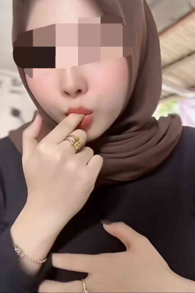 Zana, a slim and toned woman in a hijab, touches her lips.