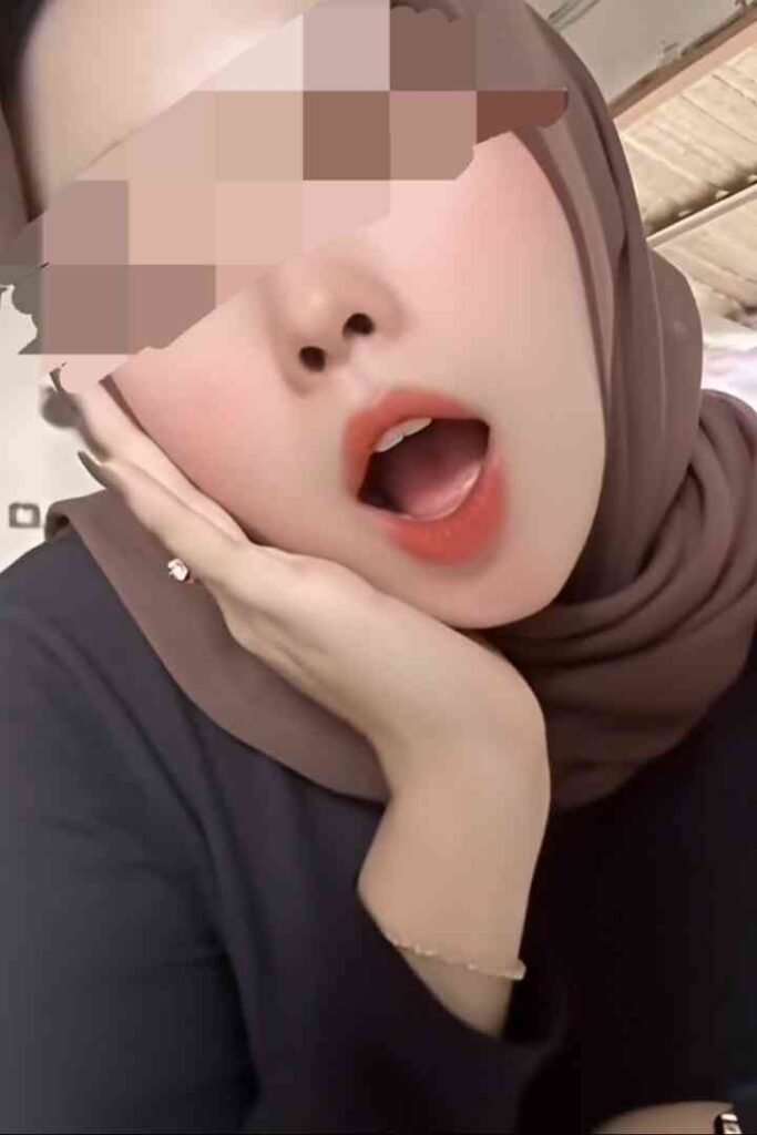 Young woman in hijab with open mouth, showing makeup and jewelry