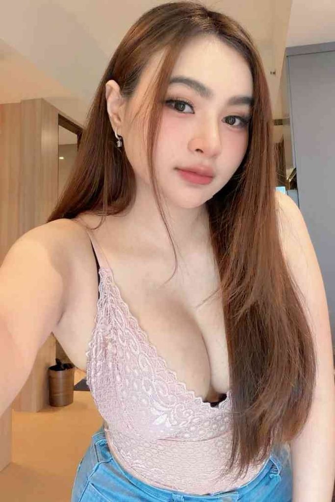 Young woman with long brown hair wearing a pink lace top.