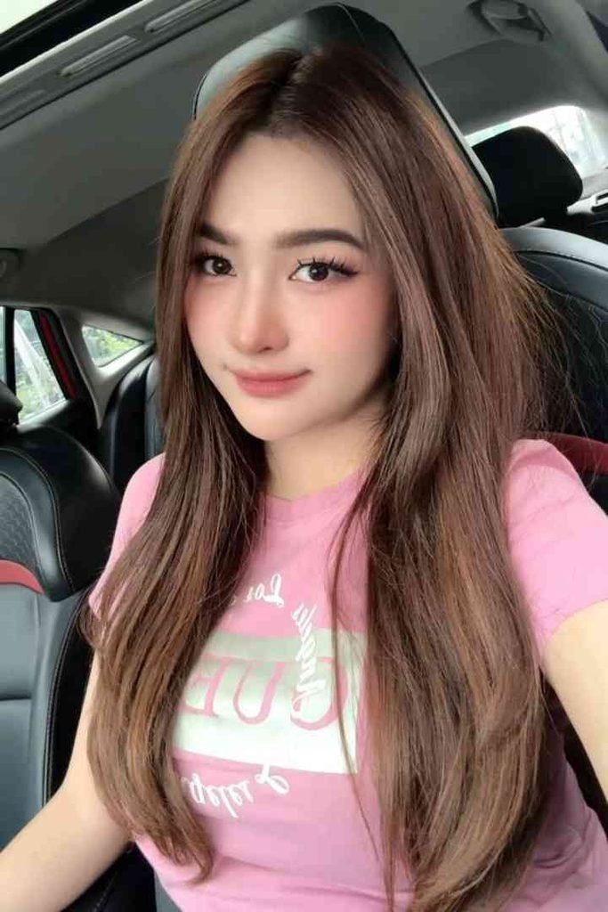 Young woman with long brown hair and pink shirt